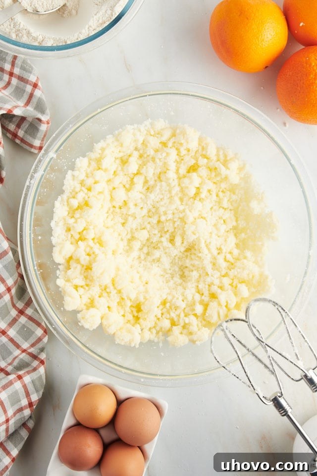 Overhead view of creamed unsalted butter and granulated sugar in a clear glass mixing bowl, looking light and fluffy.