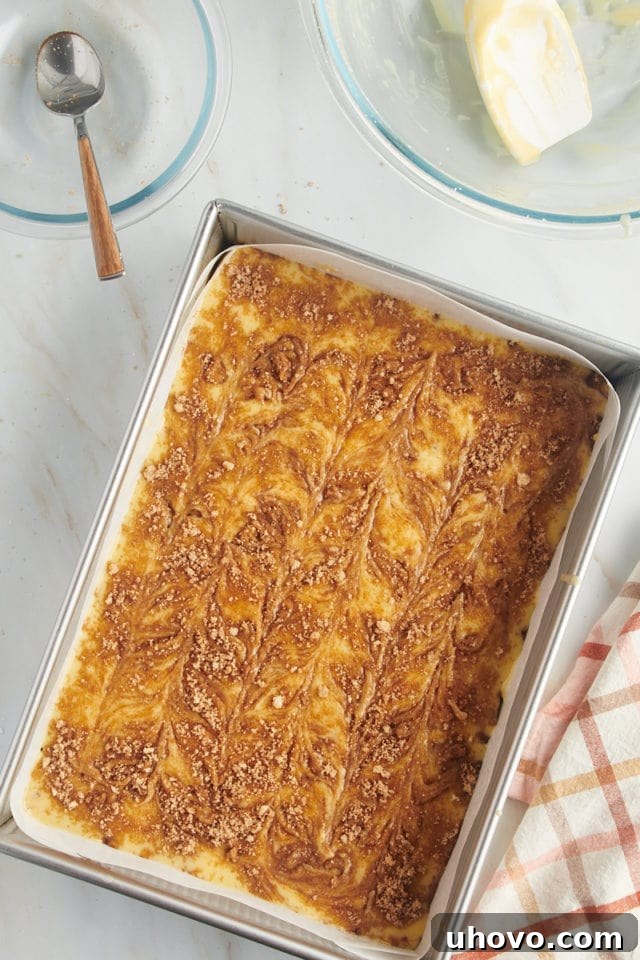The unbaked honey bun cake in its pan, showing the artful swirl of cinnamon and brown sugar on top, promising a delicious outcome.