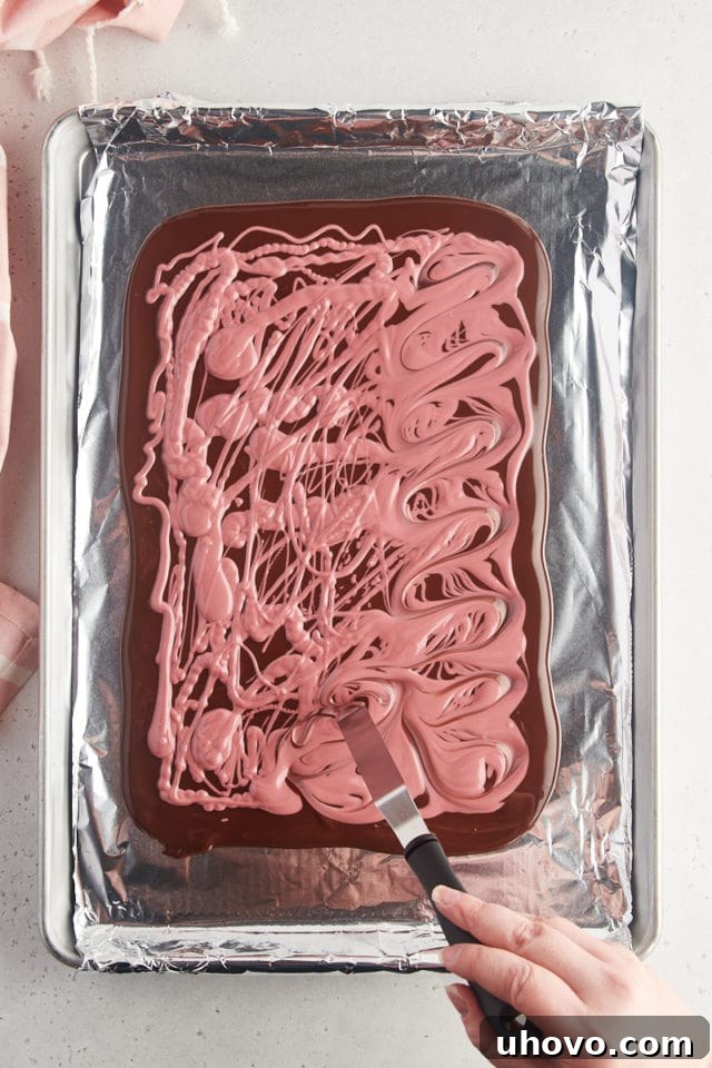 Overhead view of ruby chocolate being delicately swirled into the dark chocolate base, creating a beautiful marbled effect.