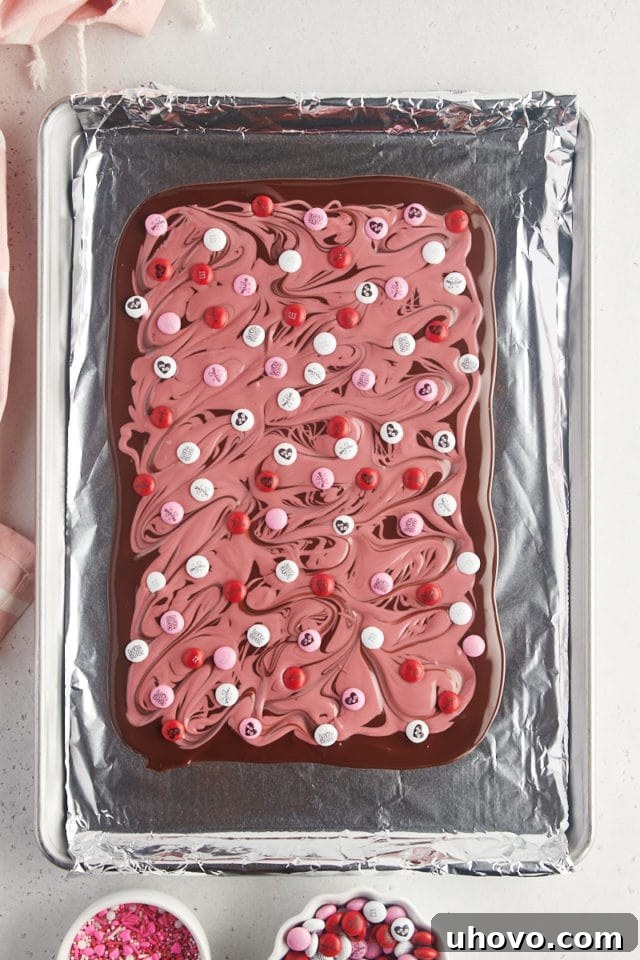 Overhead view of dark and ruby chocolate marbled bark, now topped with festive Valentine's M&M candies, adding color and texture.