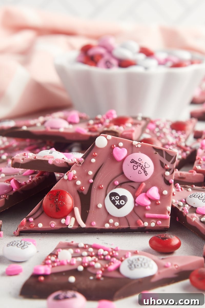 A single piece of marbled Valentine's bark surrounded by more bark and a bowl of M&Ms, tempting and ready to be picked up.