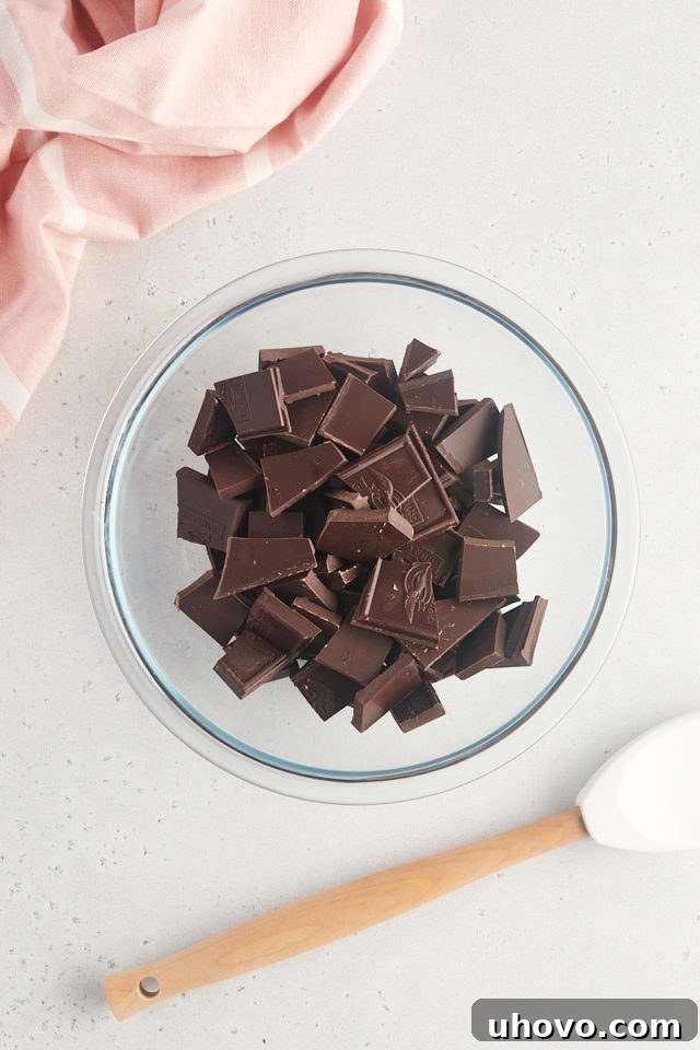 Overhead view of dark chocolate pieces in a glass bowl, ready for melting.