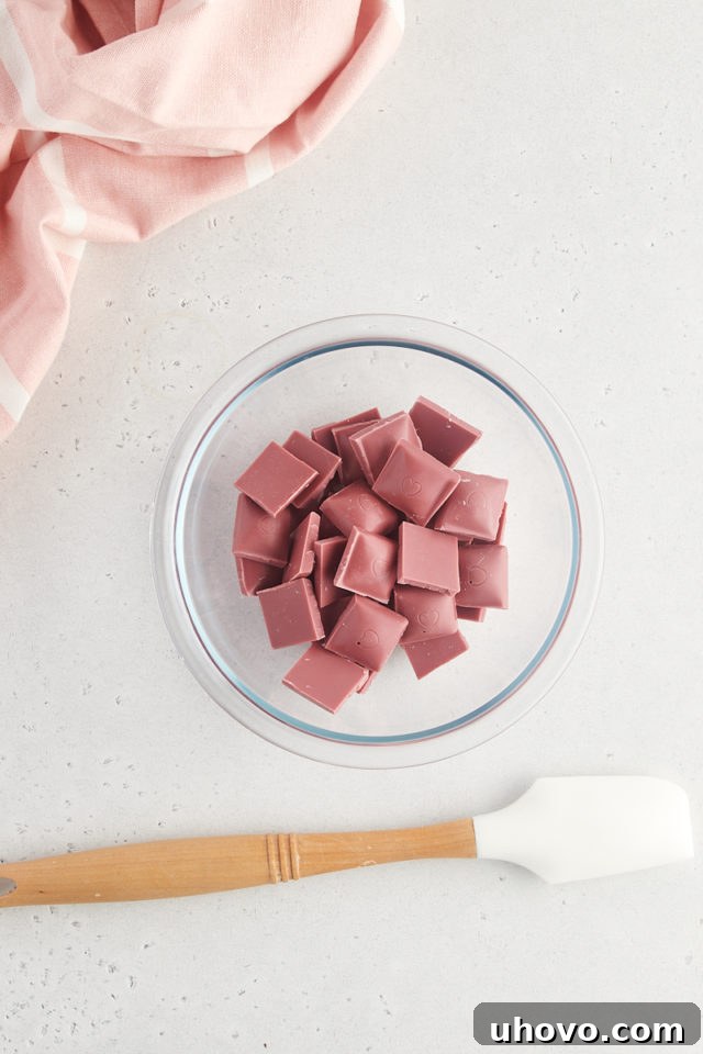 Overhead view of ruby chocolate pieces in a glass bowl, ready to be melted.