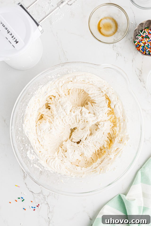 Overhead view of smooth, creamy vanilla buttercream frosting in a glass mixing bowl, perfectly prepared for piping onto cupcakes.
