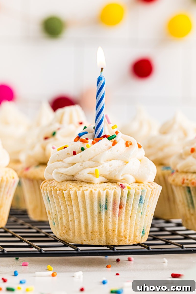 A festive confetti cupcake with a single blue birthday candle stuck in its center, ready to be lit for a celebration.