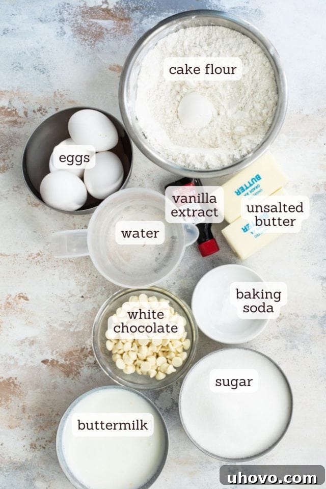 Overhead view of essential ingredients for butter pecan cake, such as eggs, flour, buttermilk, and chopped white chocolate.