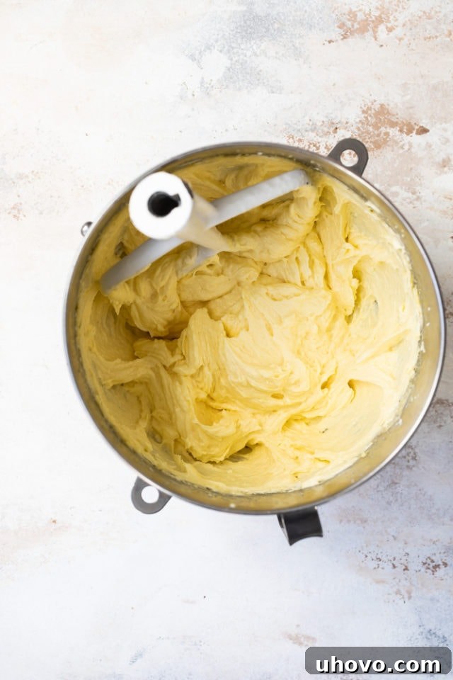 Overhead view of partially mixed cake batter in a metal mixing bowl, showcasing the creamy texture before final additions.