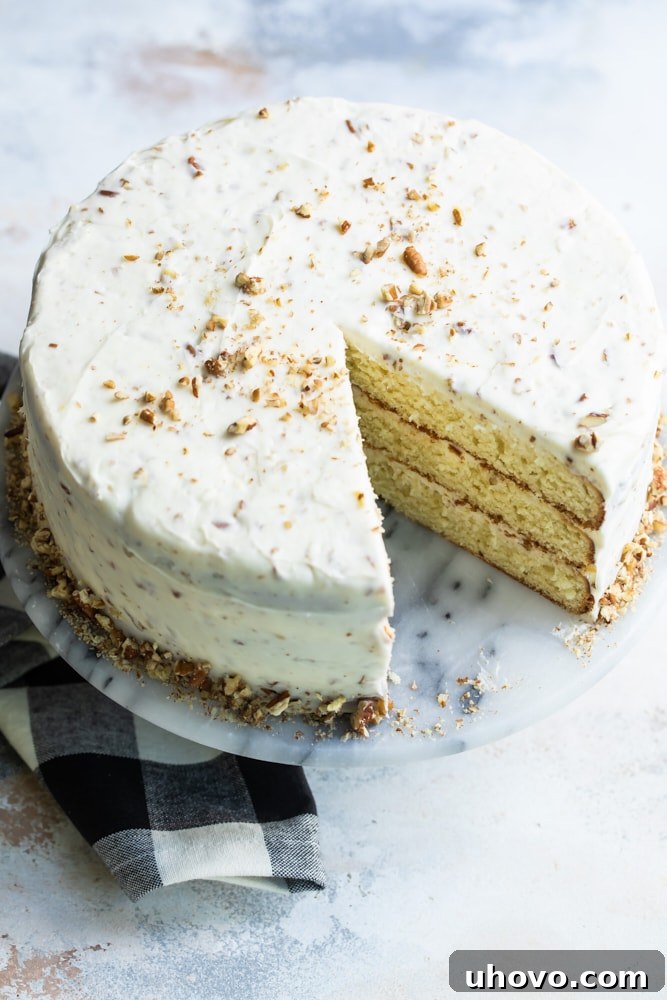 A glorious Butter Pecan Cake, fully frosted and garnished with pecans, resting on a marble cake stand, ready to be served.