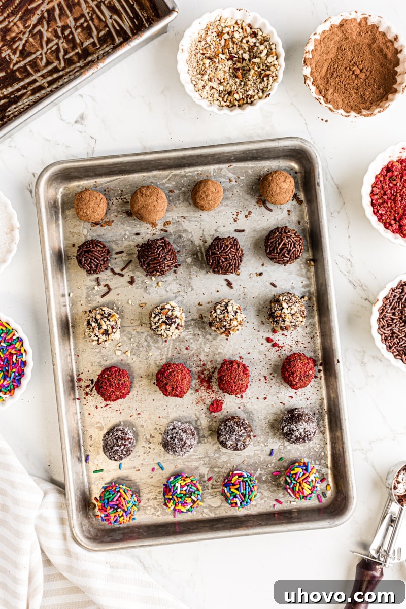 An inviting overhead view of various homemade chocolate truffles, each coated differently with toppings like cocoa, sprinkles, and nuts, arranged artfully on a baking sheet.