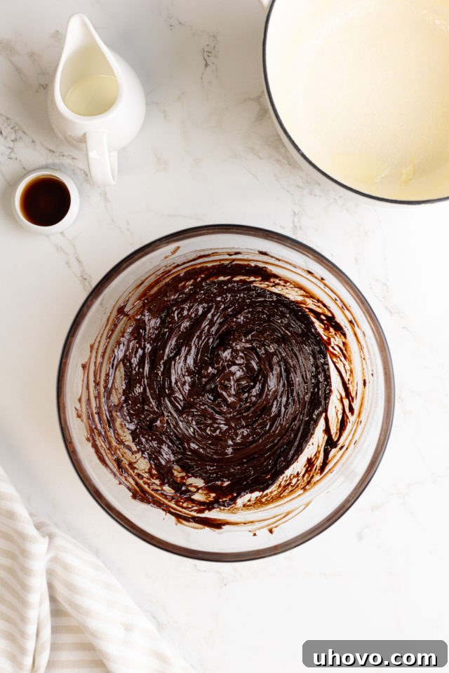 An overhead view of the smooth, glossy, and perfectly mixed chocolate ganache in a glass bowl after stirring, showing its rich, consistent texture.