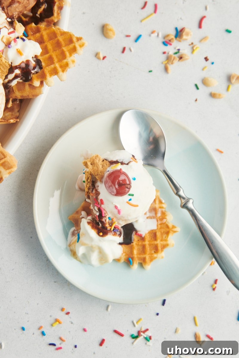 A close-up overhead view of a single serving of ice cream nachos on a light blue plate, featuring a spoonful of ice cream, waffle cone, and chocolate sauce, ready to be eaten.
