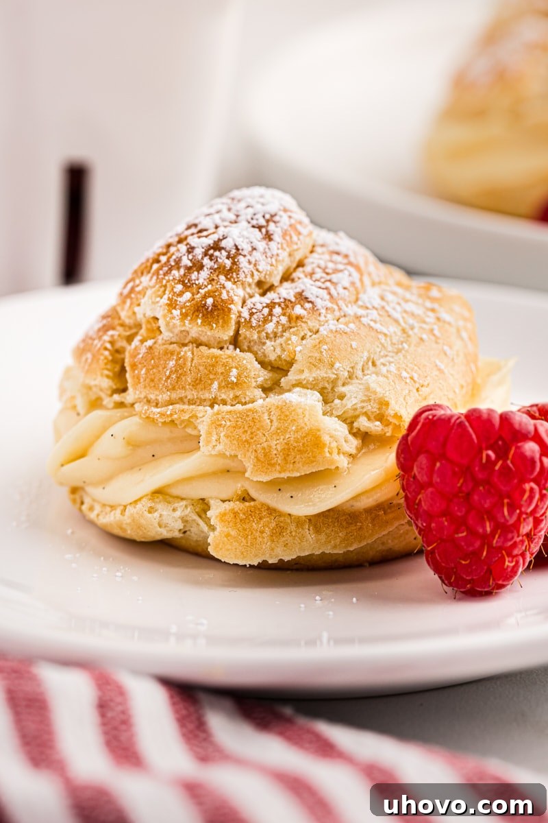 A perfectly baked golden cream puff served on a pristine white plate, showcasing its fluffy texture and inviting appearance.