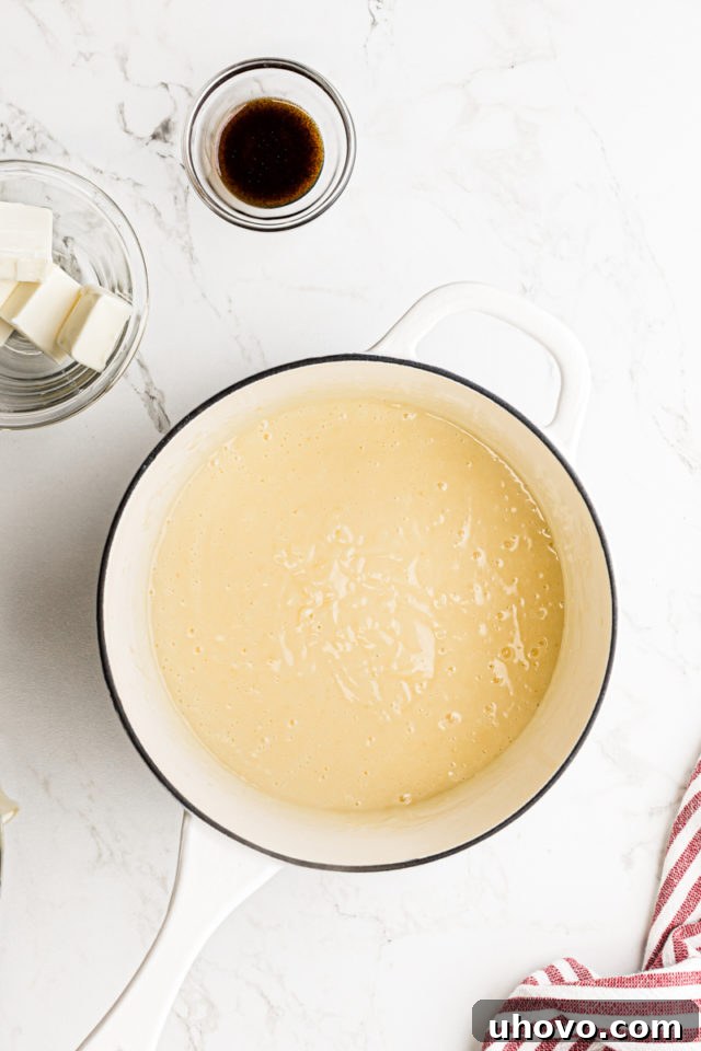 Thickened and cooked pastry cream resting in a saucepan, showing its smooth and glossy texture, ready for the addition of butter and vanilla.