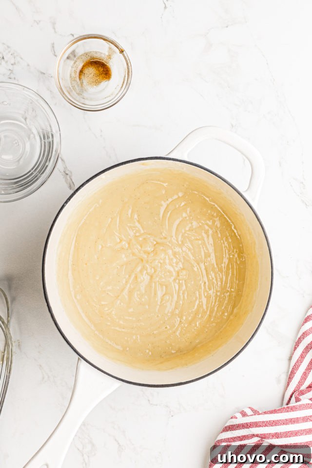 Finished pastry cream, smooth and lustrous, resting in a saucepan after butter and vanilla have been incorporated, ready to be chilled.