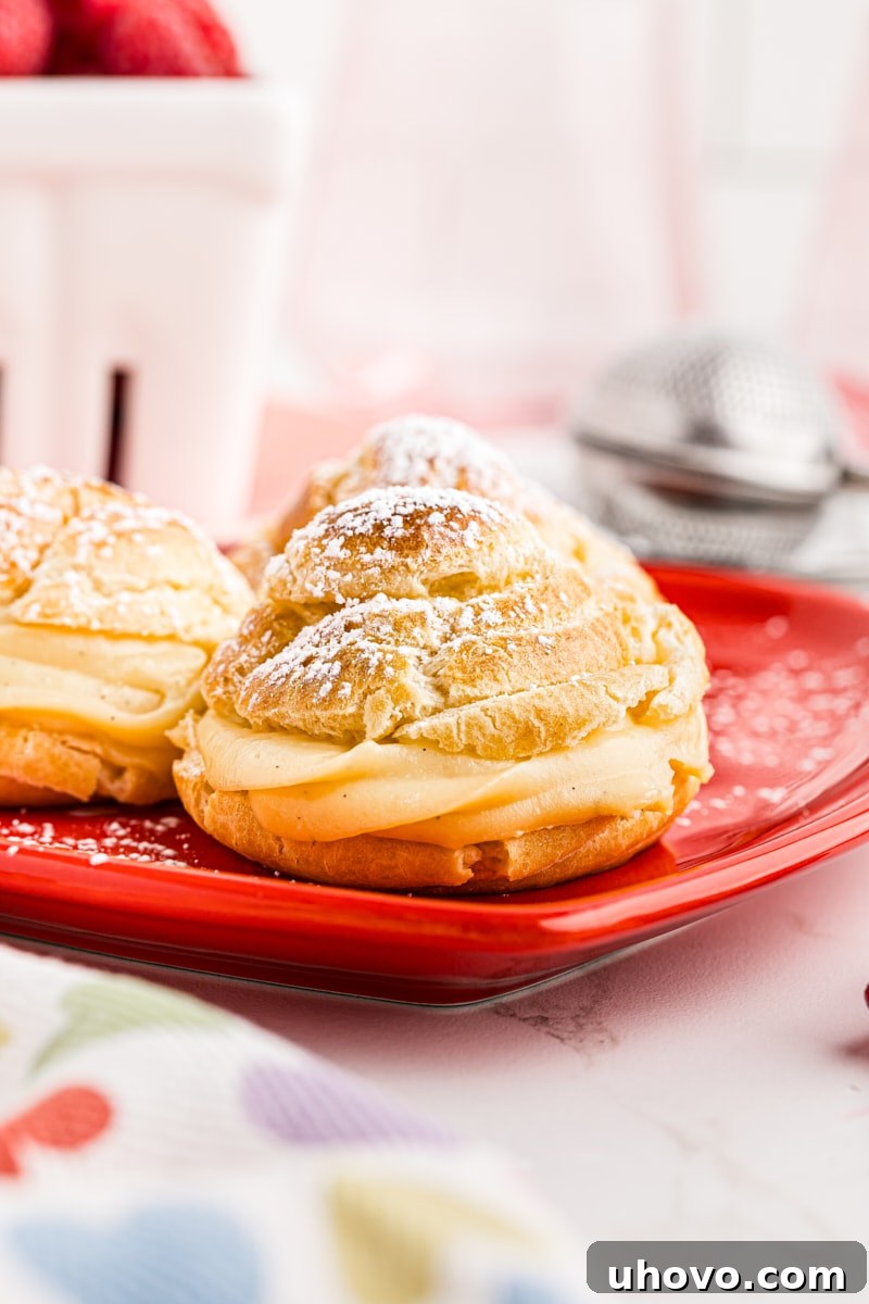 Three elegant cream puffs, perfectly golden and dusted with powdered sugar, arranged on a charming red heart-shaped plate, ideal for a romantic occasion.