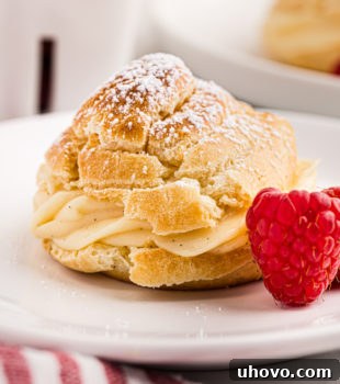 A cream puff served on a white plate, highlighting its golden exterior and creamy filling.