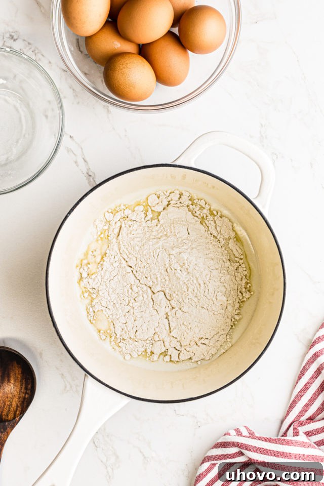 Sifted all-purpose flour being added to the hot liquid ingredients in a saucepan for pâte à choux dough.