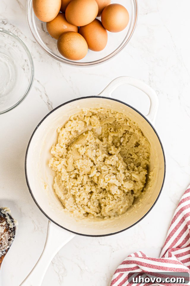 Close-up overhead view of flour thoroughly mixed into the wet ingredients, forming a cohesive dough in the saucepan.