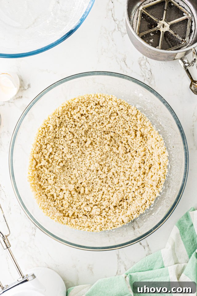Overhead view of Lofthouse cookie dough in a glass mixing bowl, mostly mixed but with a few streaks of flour visible.