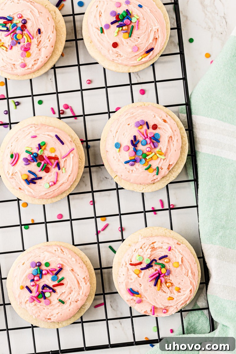 Overhead view of freshly frosted Lofthouse cookies, adorned with colorful sprinkles, cooling on a wire rack.