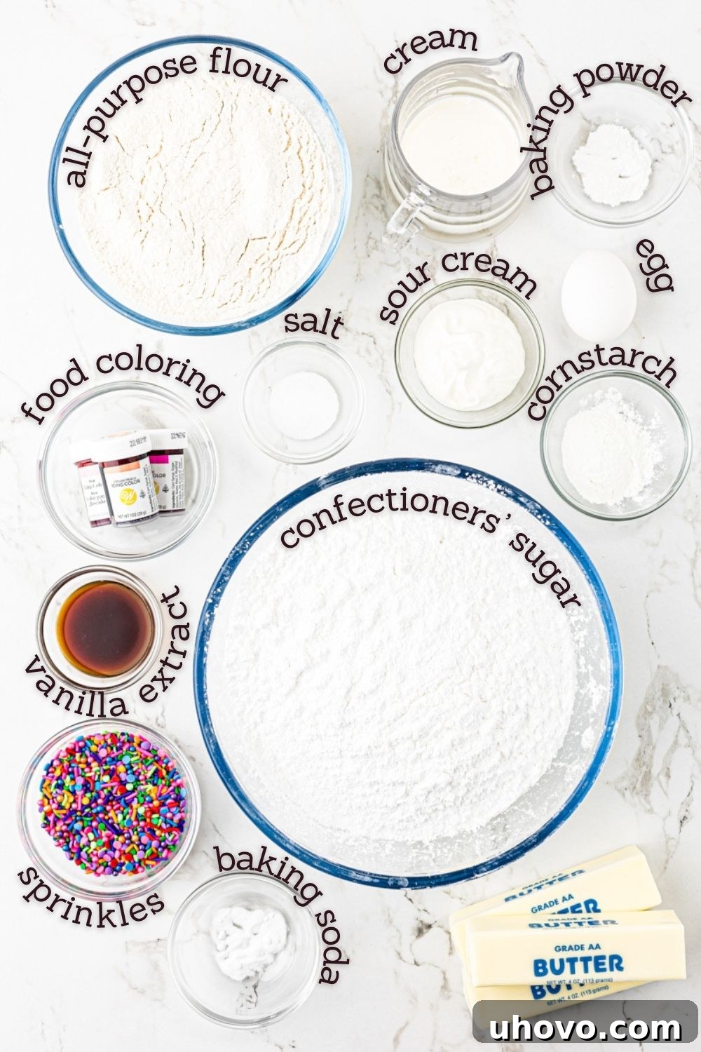 An overhead shot of various ingredients for Lofthouse cookies laid out on a clean surface, including flour, sugar, butter, and eggs.
