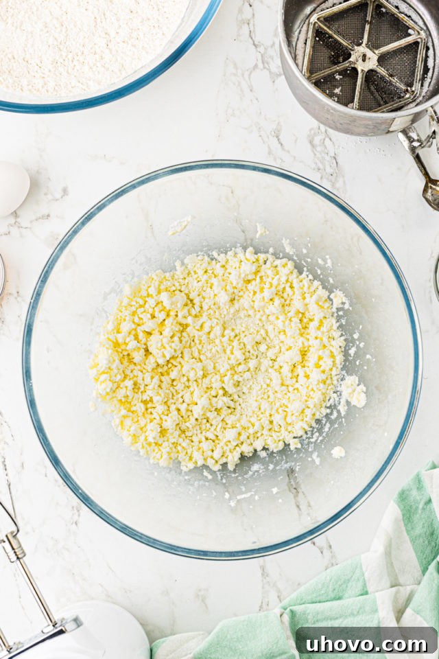 Overhead view of light and crumbly creamed butter and confectioners' sugar in a glass mixing bowl.