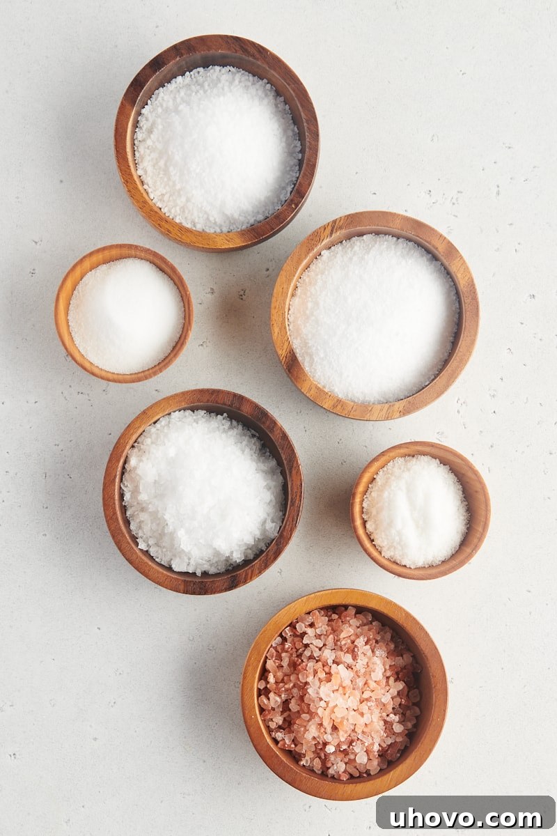 different types of salt in wooden bowls on a white surface