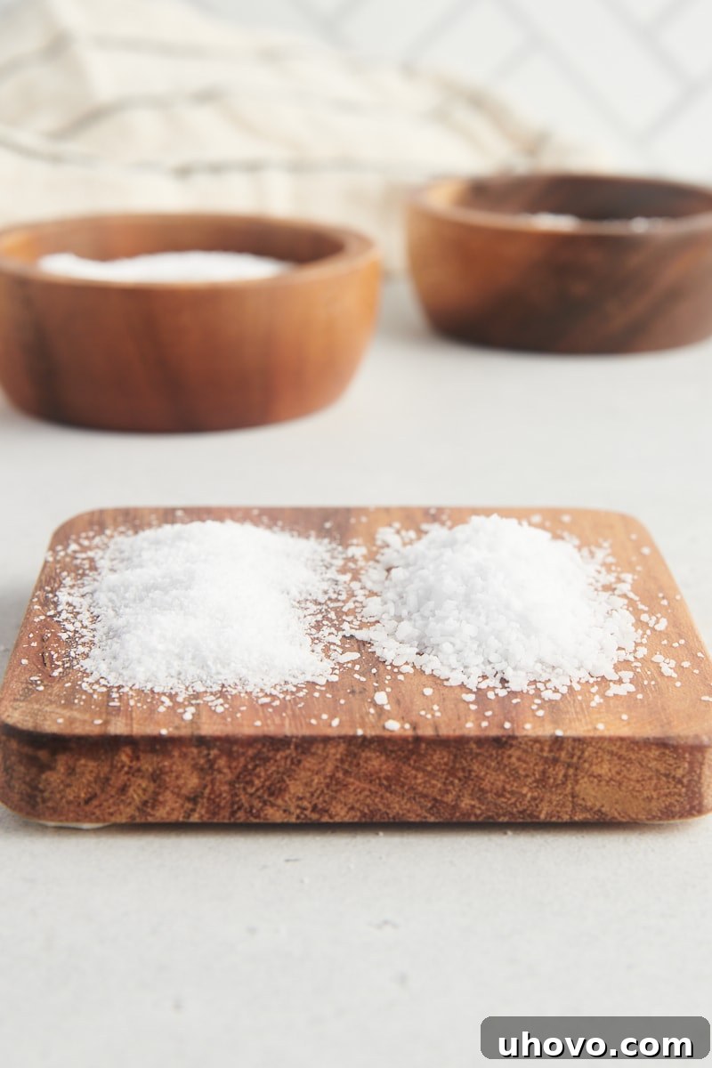 Morton kosher salt and Diamond Crystal kosher salt side by side on a small wooden board