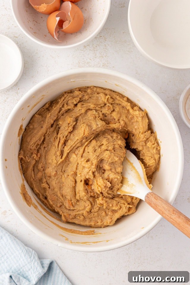 Overhead view of thoroughly mixed brown butter blondie batter resting in a white mixing bowl, ready for baking.