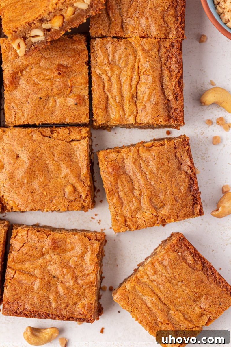 Overhead view of uniformly sliced brown butter blondies arranged neatly on parchment paper, ready for serving.