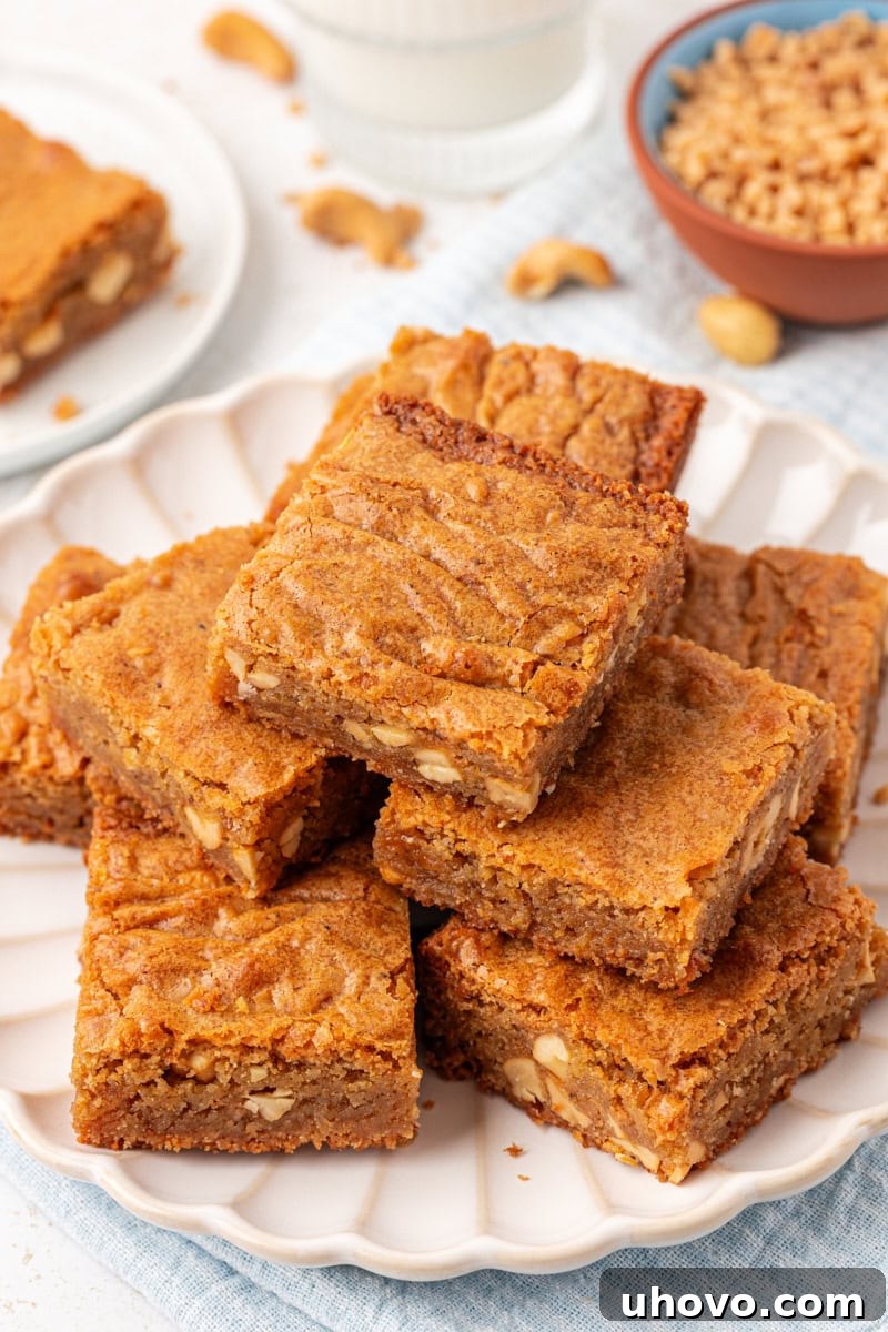 Two brown butter blondies stacked on a white plate, showcasing their rich color and inviting texture.
