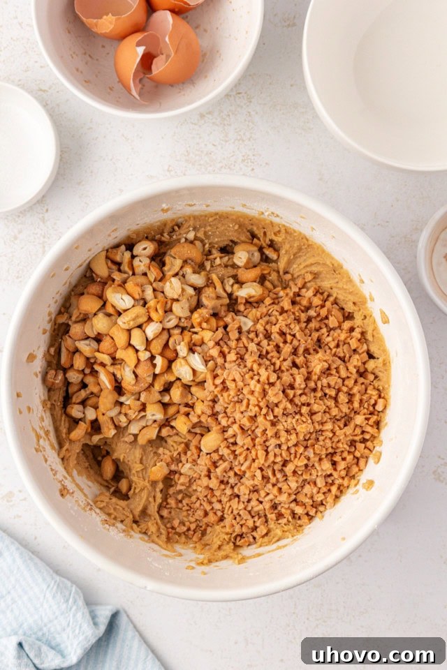 Overhead view of chopped nuts and toffee bits being stirred into the brown butter blondie batter.