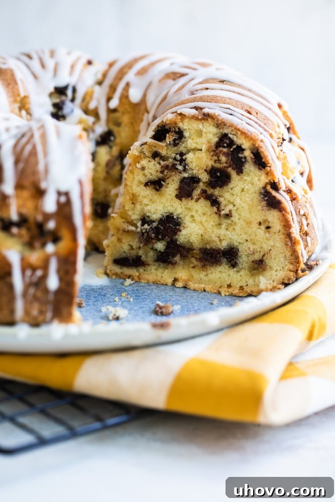 A beautifully baked and glazed Chocolate Chip Almond Bundt Cake presented on a decorative cake plate, ready for serving.