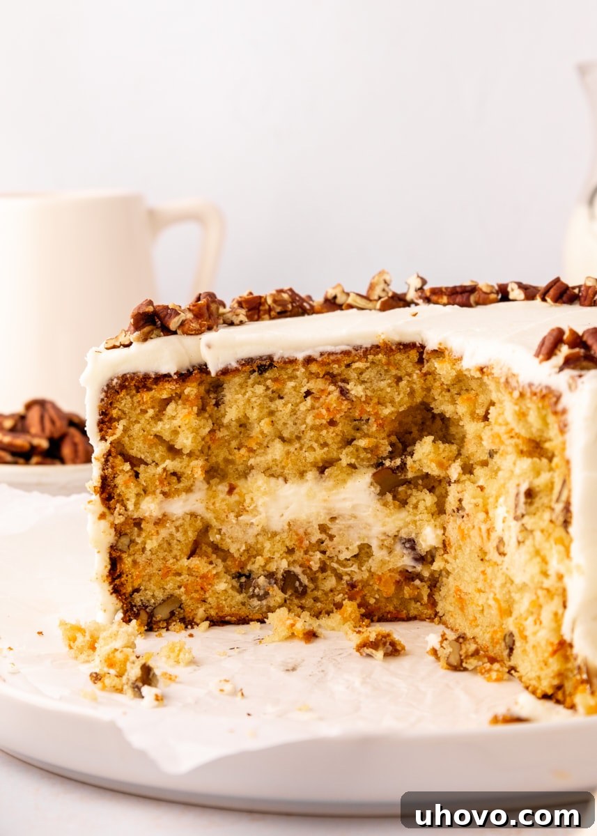 a partially cut carrot cake topped with chopped pecans, showcasing the moist cake layers and creamy frosting