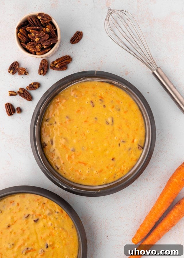 overhead view of carrot cake batter divided between two round cake pans