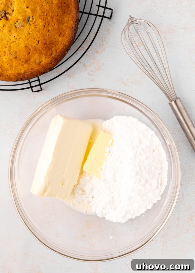 overhead view of cream cheese, butter, confectioners' sugar, and milk in a glass mixing bowl