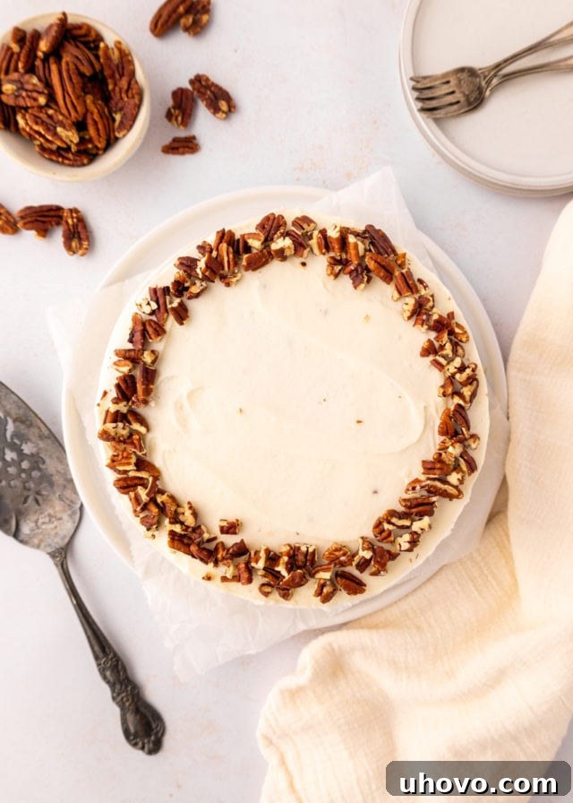 overhead view of frosted carrot cake on a white cake plate