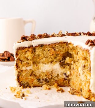 a partially cut carrot cake topped with chopped pecans, showcasing the moist cake layers and creamy frosting