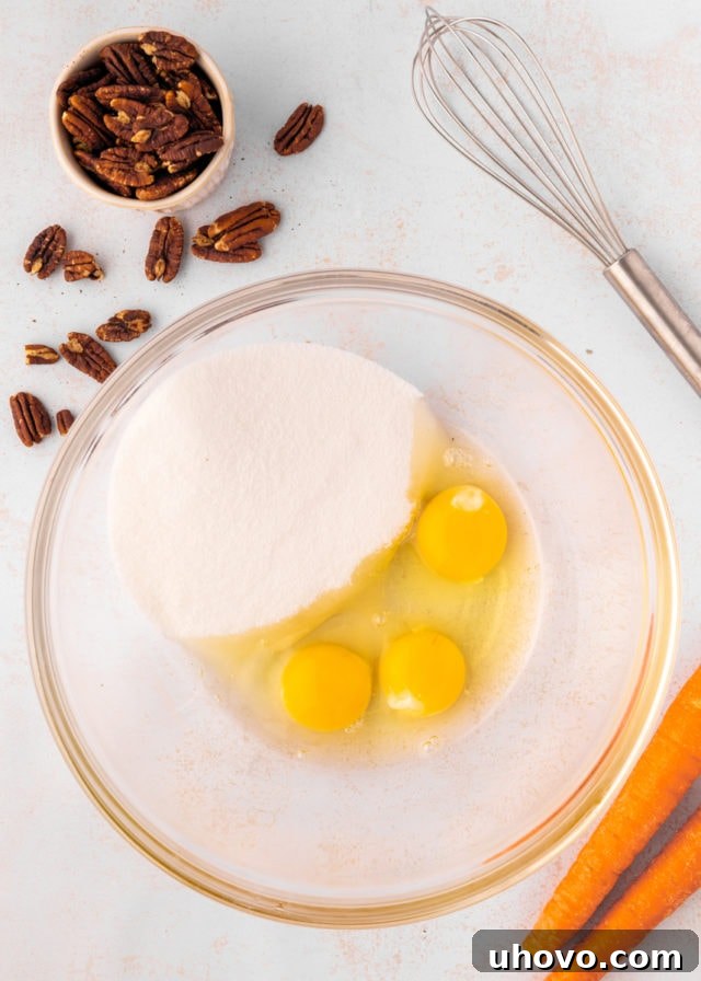 overhead view of sugar and eggs in a glass mixing bowl