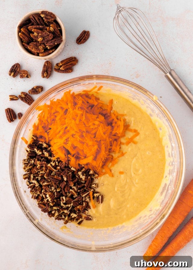 overhead view of shredded carrots and chopped pecans added to cake batter