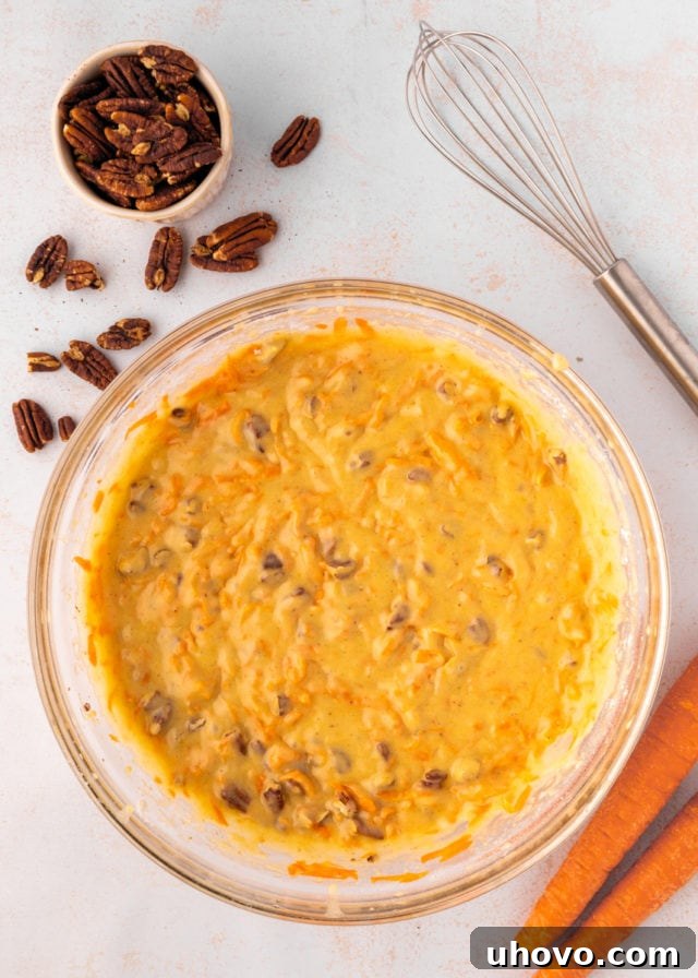 overhead view of carrot cake batter in a glass mixing bowl