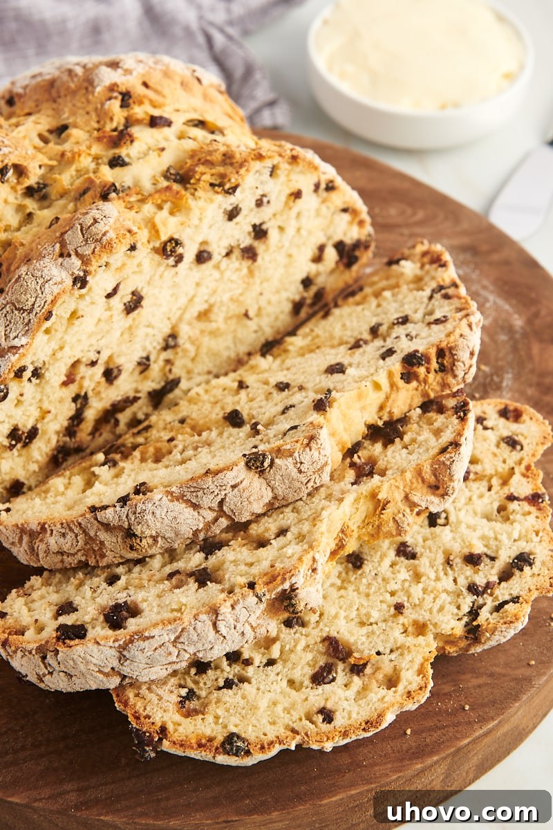 Freshly baked Irish soda bread, partially sliced, displayed on a round wooden cutting board, highlighting its golden crust and soft interior.