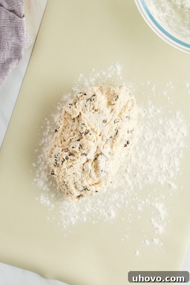 The soft, shaggy Irish soda bread dough rests on a generously floured silicone mat, ready for gentle shaping.