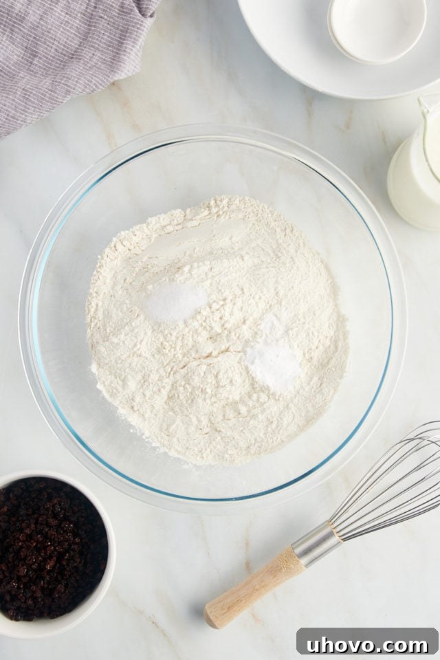 A glass mixing bowl holds precise measurements of all-purpose flour, baking soda, and salt, ready to be combined for the Irish soda bread.