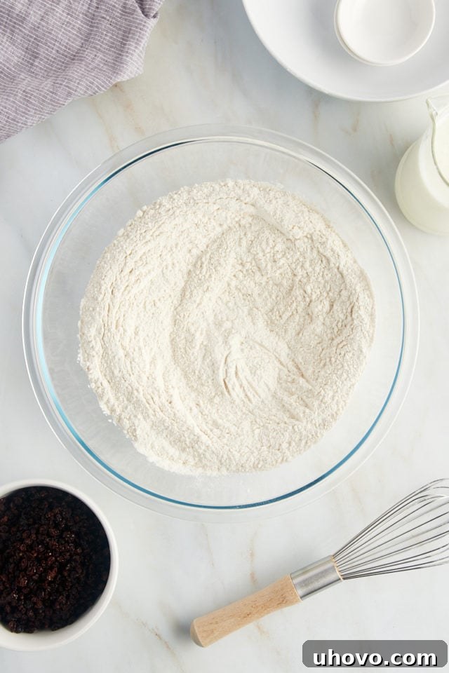 The dry ingredients for Irish soda bread—flour, baking soda, and salt—are perfectly whisked together in a glass bowl, creating a uniform mixture.