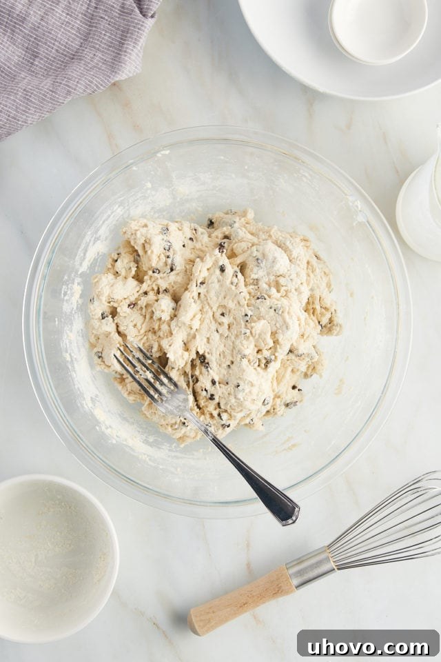 A close-up overhead view of the mixed Irish soda bread dough in a glass bowl, just coming together into a soft, slightly shaggy ball.