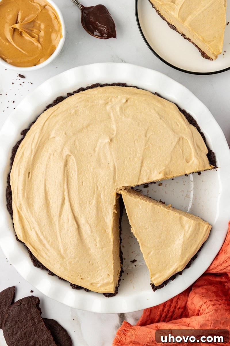 Overhead view of a complete peanut butter pie in a pie dish, with two slices already cut out.