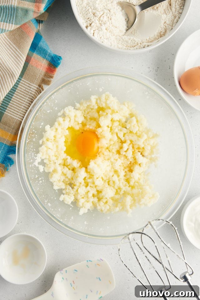overhead view of egg, vanilla extract, and almond extract added to creamed butter and sugar