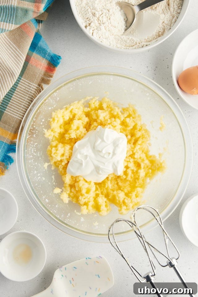 overhead view of sour cream added to partially mixed sour cream cookie dough