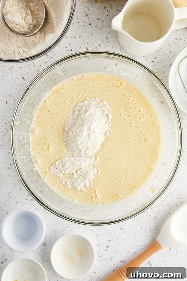 overhead view of dry ingredients added to wet ingredients for olive oil cake